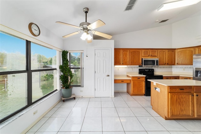 kitchen with stainless steel appliances, vaulted ceiling, light countertops, decorative backsplash, and brown cabinetry