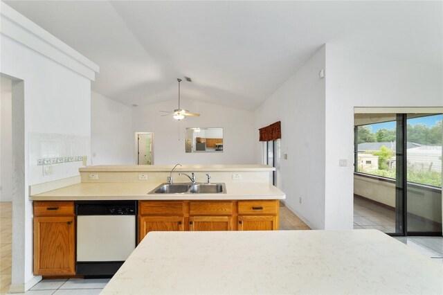 kitchen featuring dishwasher, a sink, vaulted ceiling, a peninsula, and light tile patterned flooring