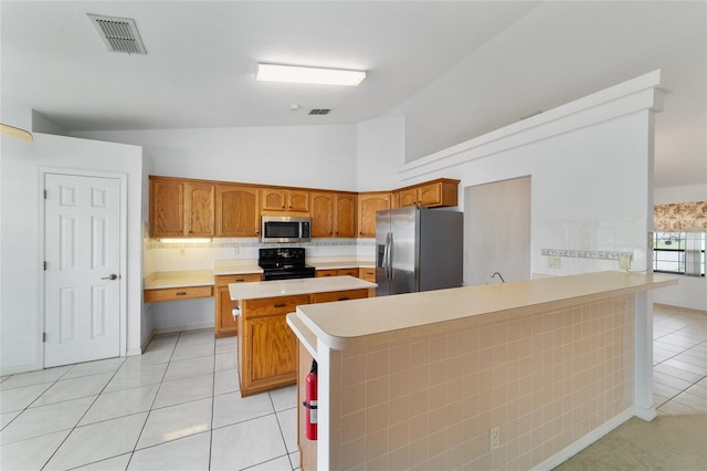 kitchen with appliances with stainless steel finishes, vaulted ceiling, a peninsula, light tile patterned floors, and light countertops