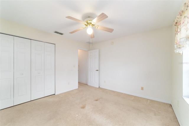 unfurnished bedroom featuring light colored carpet, a closet, baseboards, and ceiling fan