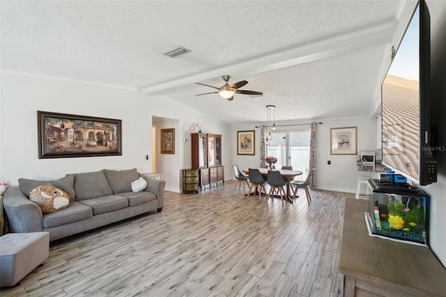living area with a textured ceiling, visible vents, light wood-style floors, and vaulted ceiling with beams