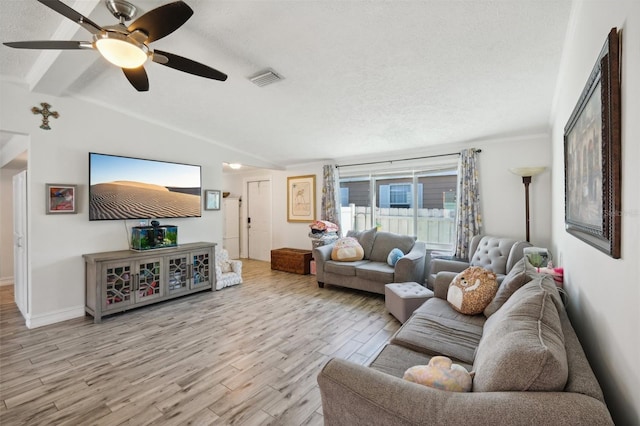 living room featuring vaulted ceiling, light wood finished floors, a textured ceiling, visible vents, and ceiling fan
