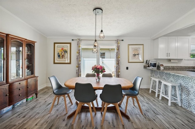 dining room with baseboards, a textured ceiling, crown molding, and wood finished floors