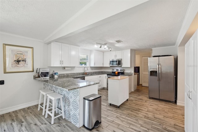 kitchen with a sink, white cabinetry, appliances with stainless steel finishes, a textured ceiling, and a peninsula