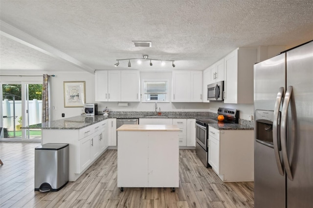 kitchen with white cabinets, light wood-style flooring, a peninsula, and appliances with stainless steel finishes