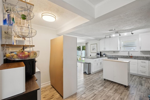 kitchen with a textured ceiling, a sink, light wood-style floors, and white cabinets