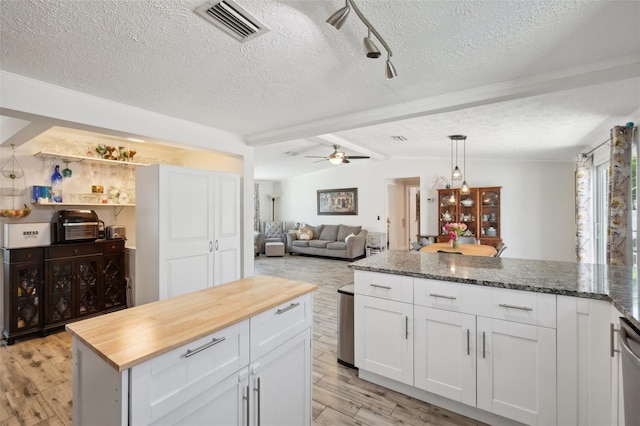 kitchen with butcher block countertops, vaulted ceiling with beams, light wood-style flooring, and visible vents
