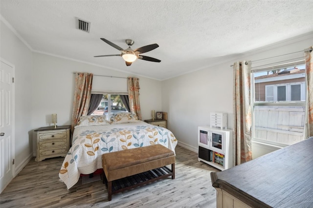 bedroom featuring visible vents, crown molding, light wood-style floors, and a textured ceiling