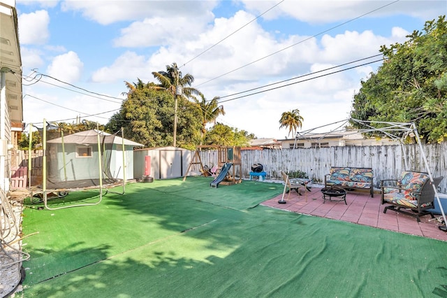 view of yard featuring a storage unit, a fenced backyard, an outdoor fire pit, and a patio area