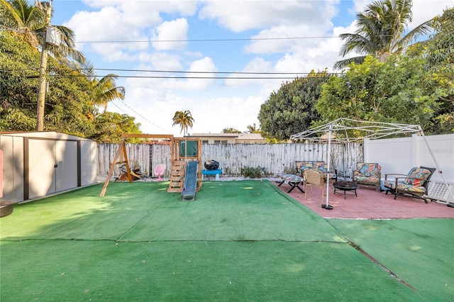 view of patio with a fenced backyard, an outdoor fire pit, a shed, and an outbuilding