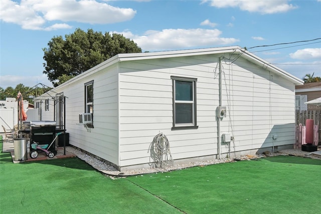 view of side of property with cooling unit, fence, and a lawn