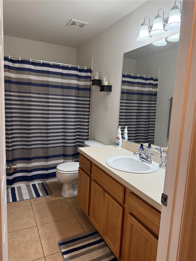 bathroom featuring a textured wall, toilet, vanity, tile patterned floors, and a textured ceiling