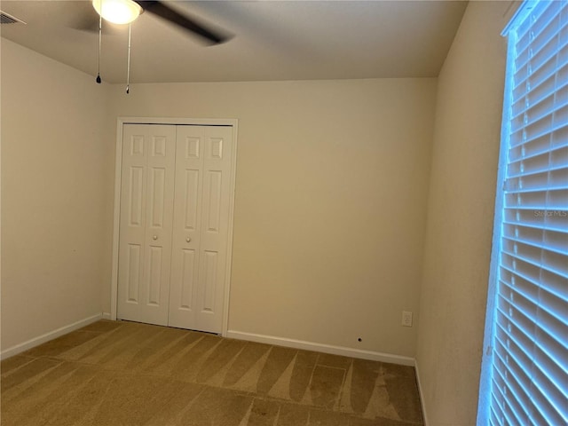 unfurnished bedroom with carpet, baseboards, a closet, and ceiling fan
