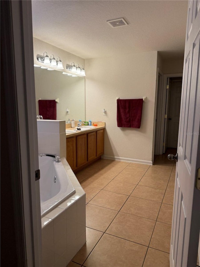 full bathroom with a bath, a textured ceiling, tile patterned floors, vanity, and baseboards