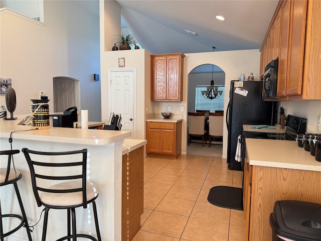 kitchen with a kitchen breakfast bar, black microwave, vaulted ceiling, light countertops, and light tile patterned floors