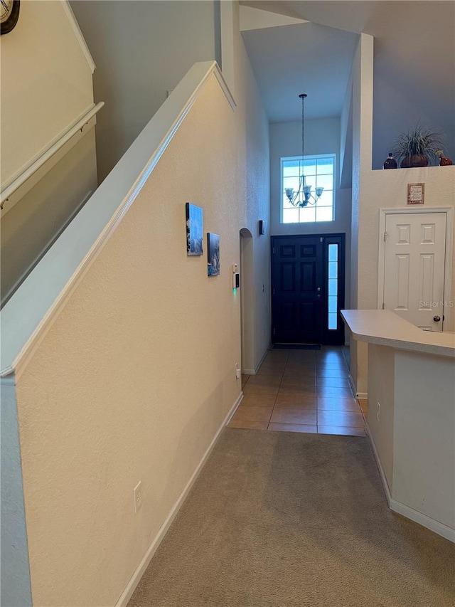 foyer entrance featuring a chandelier, baseboards, light carpet, and light tile patterned floors