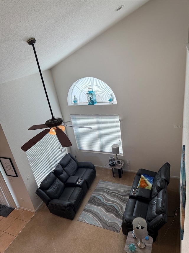 living area with ceiling fan, tile patterned flooring, a textured ceiling, and baseboards