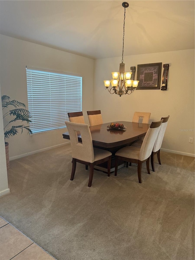 carpeted dining space with a chandelier and baseboards