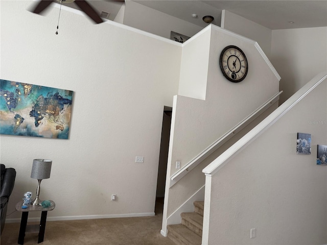 stairway featuring carpet flooring, a ceiling fan, and baseboards