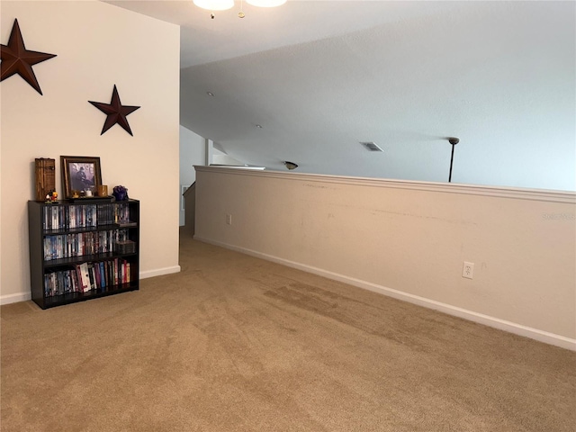 empty room featuring carpet, vaulted ceiling, and baseboards