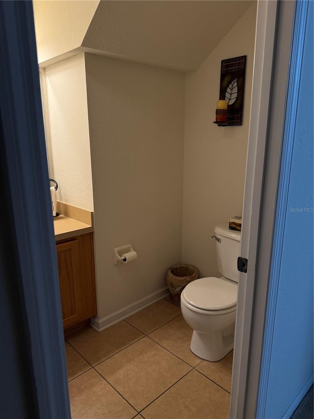 bathroom with tile patterned flooring, toilet, vanity, and lofted ceiling