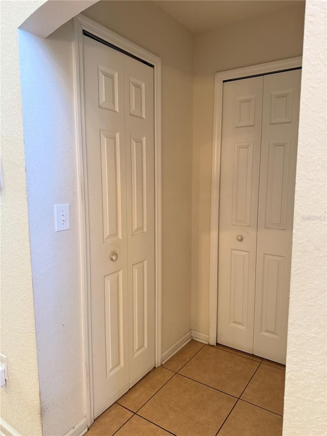 hall with light tile patterned flooring and baseboards