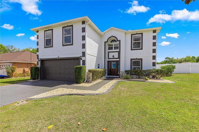 view of front of property with driveway, stucco siding, an attached garage, fence, and a front lawn