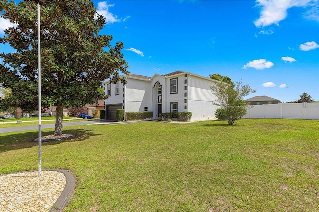 exterior space featuring driveway, stucco siding, fence, an attached garage, and a lawn