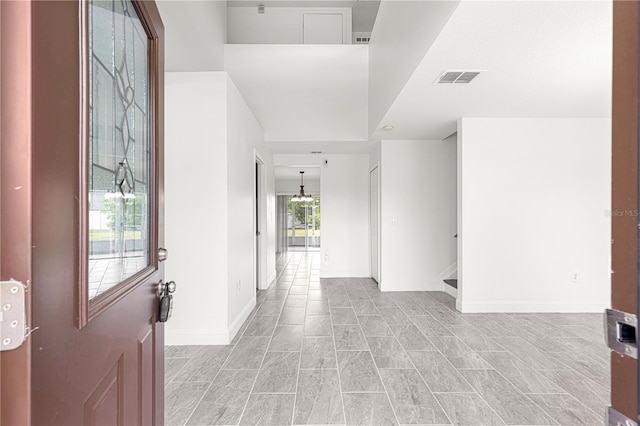 entrance foyer with baseboards, visible vents, and a towering ceiling