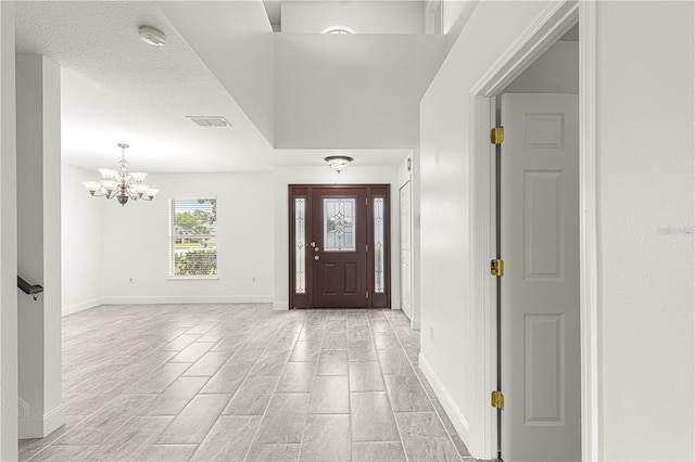 entrance foyer featuring an inviting chandelier, baseboards, and visible vents