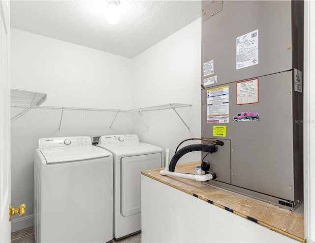 laundry room featuring heating unit, washer and dryer, laundry area, and a textured ceiling
