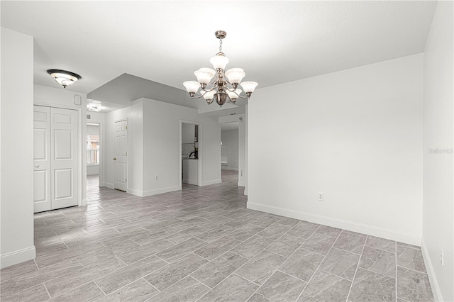 unfurnished room with baseboards and a notable chandelier
