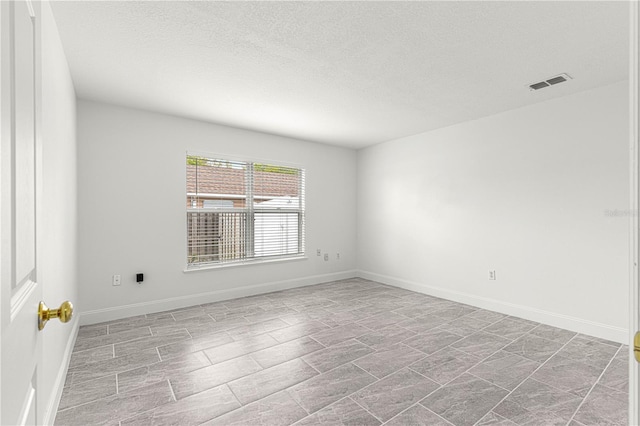 empty room with a textured ceiling, baseboards, and visible vents