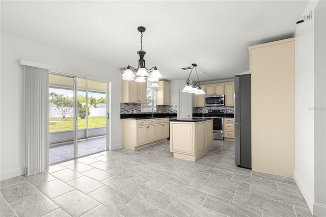 kitchen featuring backsplash, a chandelier, appliances with stainless steel finishes, dark countertops, and cream cabinetry