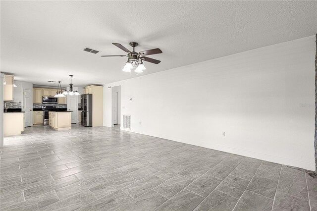unfurnished living room featuring ceiling fan with notable chandelier, baseboards, a textured ceiling, and visible vents