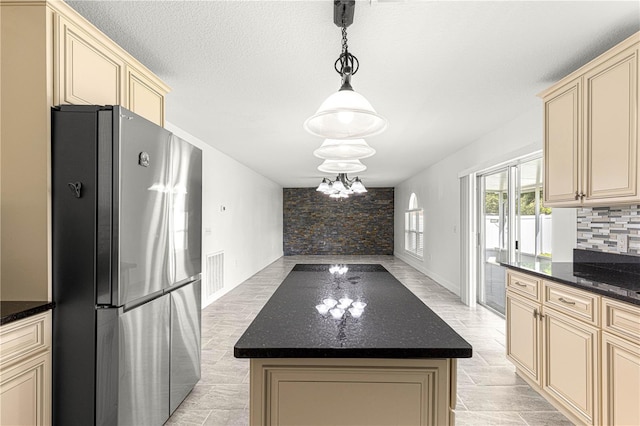 kitchen featuring cream cabinets, visible vents, and freestanding refrigerator