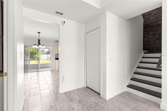 interior space with baseboards, a textured ceiling, visible vents, and an inviting chandelier