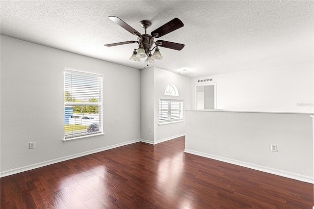 spare room with a textured ceiling, visible vents, baseboards, wood finished floors, and a ceiling fan