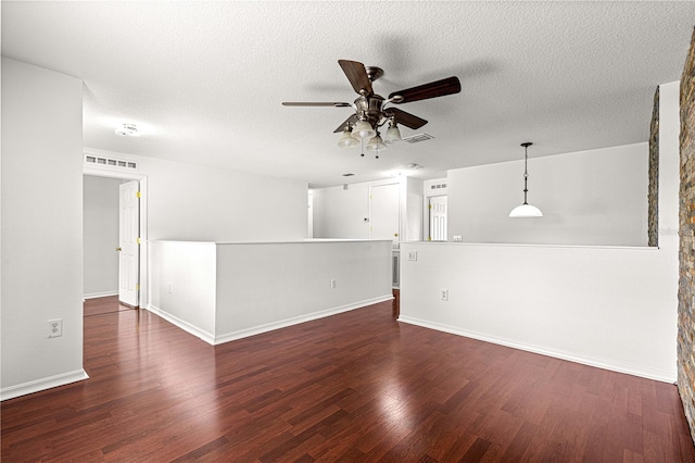 empty room with a textured ceiling, visible vents, baseboards, ceiling fan, and wood finished floors