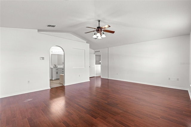 unfurnished living room with vaulted ceiling, dark wood finished floors, visible vents, arched walkways, and ceiling fan