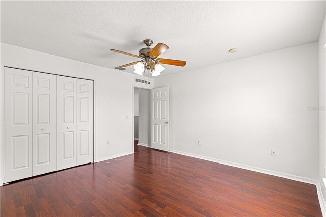 unfurnished bedroom with a closet, visible vents, wood finished floors, and baseboards