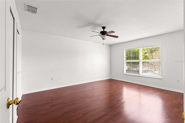 unfurnished room with dark wood-style flooring, baseboards, a textured ceiling, visible vents, and a ceiling fan