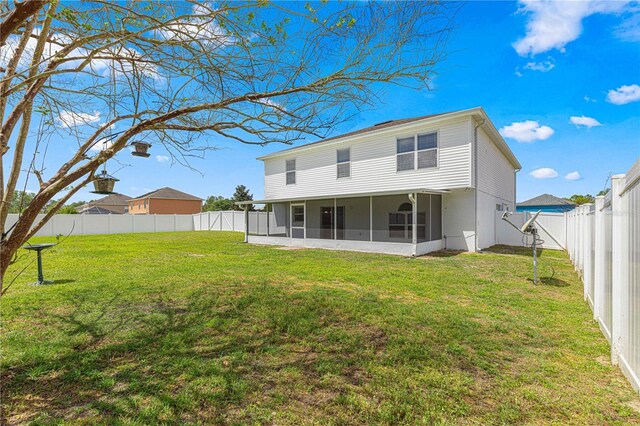 back of house with a fenced backyard, a sunroom, and a yard