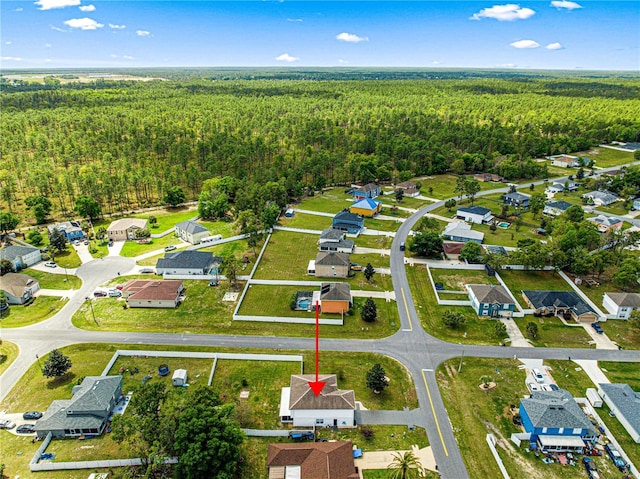 drone / aerial view featuring a wooded view and a residential view