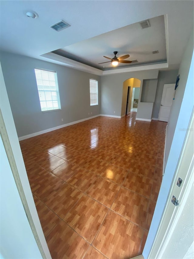 5323 SW 111th Lane Rd, Ocala, FL 34476 - tiled empty room featuring a tray ceiling, plenty of natural light, a ceiling fan, and arched walkways