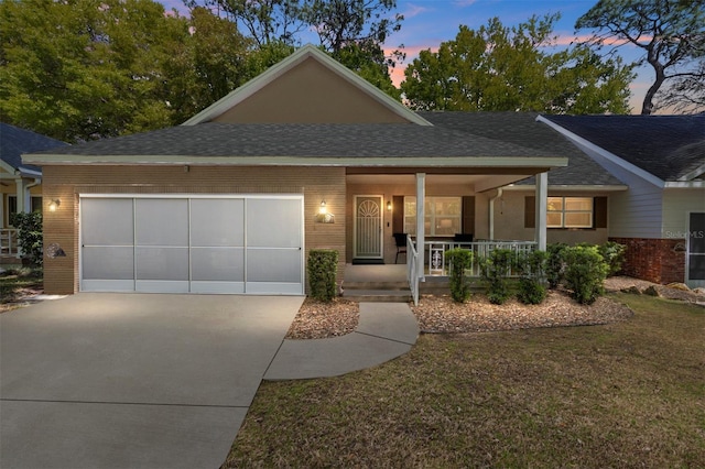 view of front of home featuring covered porch, concrete driveway, an attached garage, brick siding, and a lawn