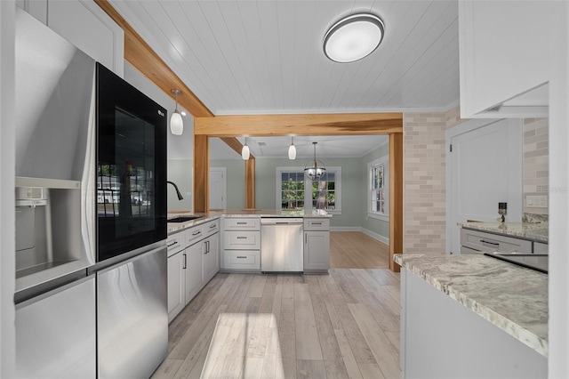 kitchen with appliances with stainless steel finishes, a sink, ornamental molding, a peninsula, and light wood-style flooring