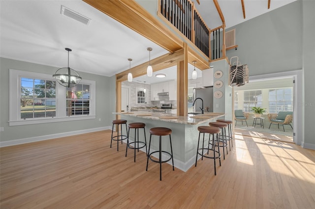 kitchen featuring appliances with stainless steel finishes, white cabinetry, a breakfast bar area, light wood-style flooring, and baseboards