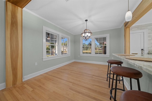 dining room with light wood finished floors, ornamental molding, baseboards, and a chandelier