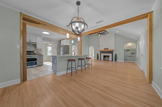 kitchen featuring stainless steel appliances, lofted ceiling, under cabinet range hood, a breakfast bar, and white cabinets